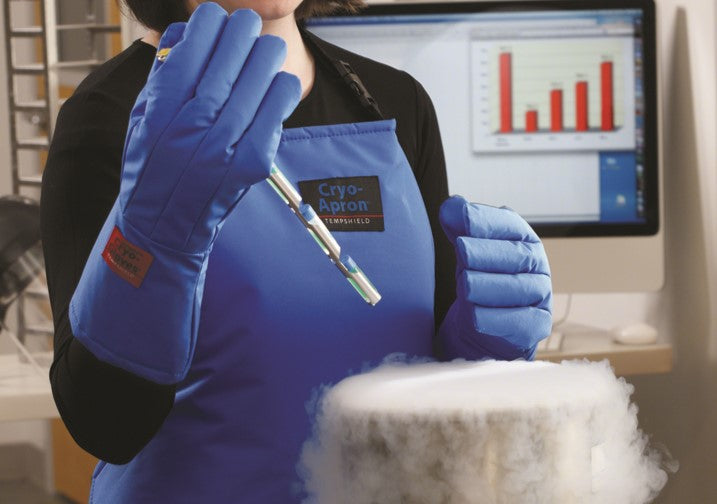 Female holding a cryo cane above a container with liquid nitrogen gas, wearing a blue cryo-apron and blue waterproof cryo gloves. 