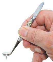 a hand using a pen like tool with a flat bottom on a metal pin with a flat round top