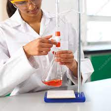 a scientist holding a vial of orange liquid 